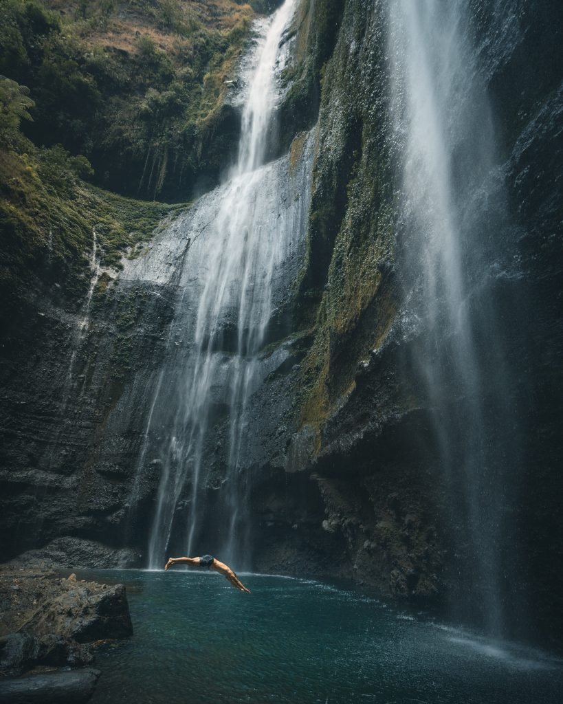 person in black short diving in water 3218134