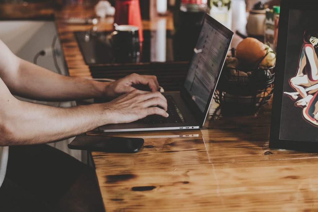 person in front of laptop on brown wooden table 2115217
